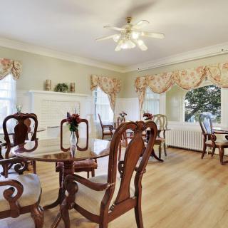 A traditional dining room with elegant wooden chairs and a ceiling fan.