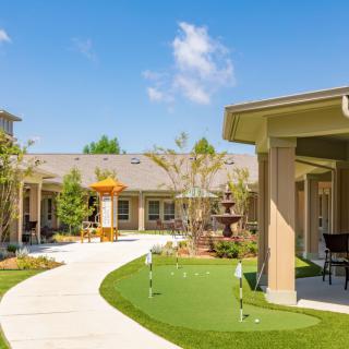 A tranquil courtyard with a winding pathway and well-maintained garden on a sunny day.