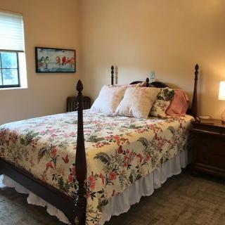 A cozy bedroom with a floral quilt on the bed and a lamp on the bedside table.