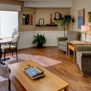 A cozy and modern living room with comfortable chairs, a coffee table, wooden flooring, and decorative items.