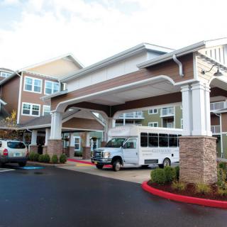 A residential building entrance with parked vehicles in the driveway.