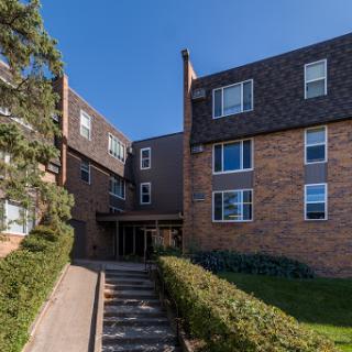 A modern brick apartment building with a landscaped entrance.
