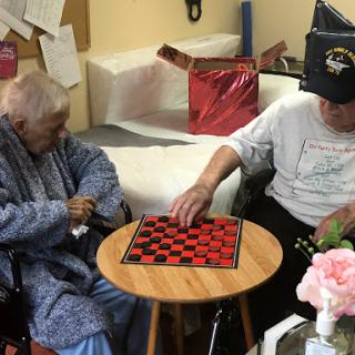 Two elderly individuals engaged in a game of checkers, enjoying each other's company.