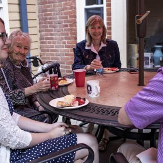 A group of people enjoying a meal and conversation at an outdoor table.