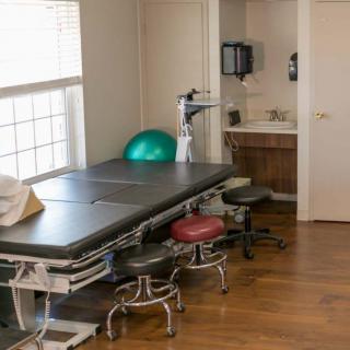 A medical office with a treatment table, exercise ball, and stools.