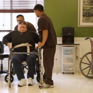 A patient receiving assistance from caregivers while seated in a wheelchair.