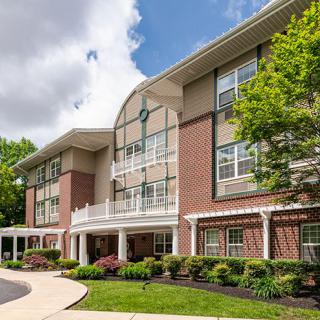 A modern residential building with landscaped surroundings and a clear sky.