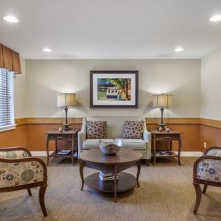 A cozy living room with a sofa, chairs, coffee table, and artwork on the wall.