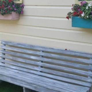 A wooden bench sits in front of a wall with colorful flower boxes.
