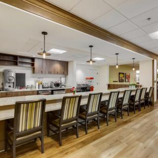 Modern kitchen area with a long counter and bar stools.