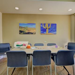 A modern conference room with a large table, surrounded by chairs and decorated with colorful artwork on the walls.