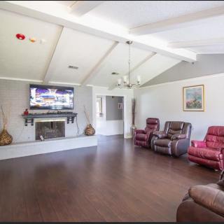 A spacious living room with a vaulted ceiling, featuring a modern fireplace and hardwood flooring, equipped with comfortable recliner chairs and a television.