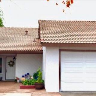 A residential house featuring a tiled roof and a white garage door.