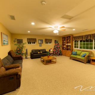 A cozy living room with sofas, a coffee table, bookshelves, and a decorated Christmas tree.