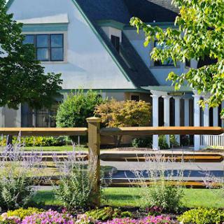 A beautifully landscaped home with a wooden fence and vibrant flowers.