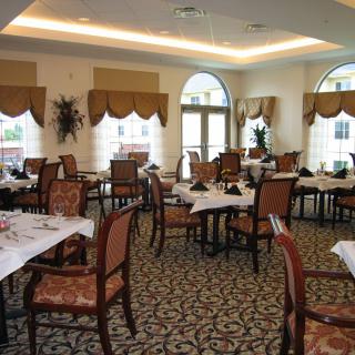 An elegant restaurant dining room with neatly arranged tables and chairs, featuring warm lighting and decorative elements.