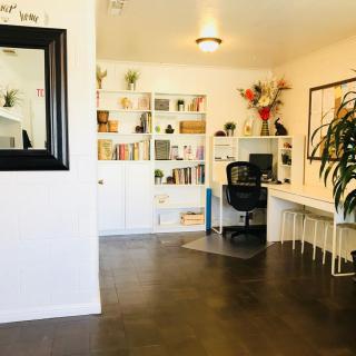 A clean and organized home office with a large bookshelf, desk, and plants.