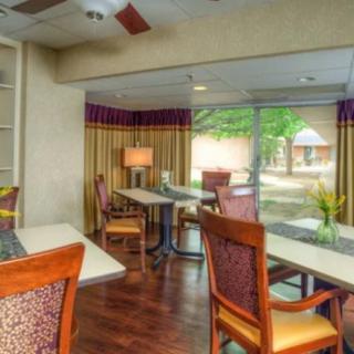 A cozy room with tables and chairs, featuring large windows that let in plenty of natural light.