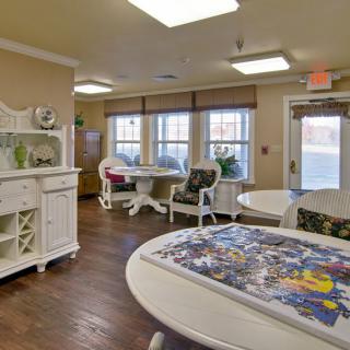 A cozy indoor room with tables and chairs, featuring a partially completed puzzle on one table.