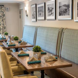 A cozy restaurant interior with neatly set tables and upholstered seating.