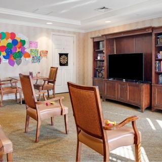 A cozy living room featuring a seating area with a large TV and colorful wall art.