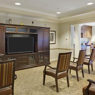 A cozy living room with a television and several chairs arranged in front.