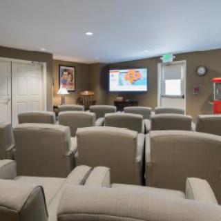 A cozy home theater with rows of comfortable seating facing a large screen.