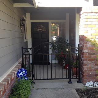 A cozy front porch with a gated entry and potted plants.