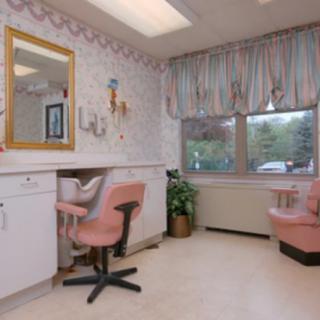 A cozy beauty salon interior featuring pink chairs and a large mirror.