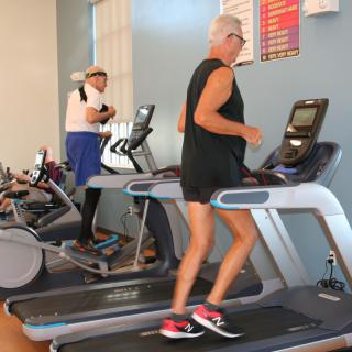 Two people exercising on treadmills in a gym.