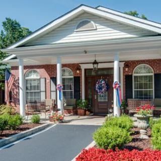 A well-maintained building with a landscaped entrance, featuring columns and patriotic decorations.