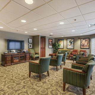 A comfortable waiting room with multiple chairs and a TV, decorated with framed artwork.