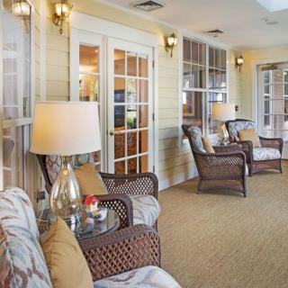 A cozy living room with wicker chairs, lamps, and large windows.