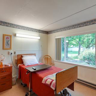 A well-lit and comfortable hospital room featuring a bed, furniture, and a scenic view from the window.