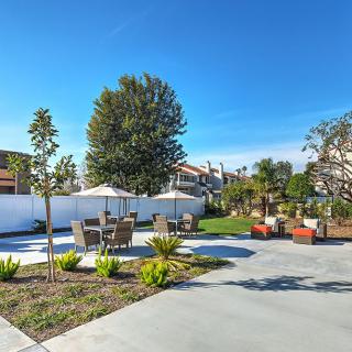 A spacious outdoor patio area with seating, surrounded by greenery and trees under a clear blue sky.