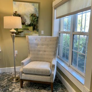 A cozy corner with a tufted armchair next to a floor lamp and window.