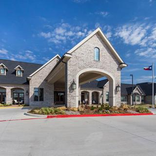 A modern residential building with a stone facade and an inviting entrance, set against a clear blue sky.