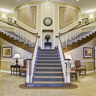 A luxurious lobby featuring a grand, carpeted staircase with symmetrical design.
