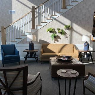 A cozy living room setup featuring a mix of modern and classic furniture, illuminated by natural light.
