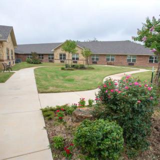 A well-maintained garden with pathways leading to a brick building.