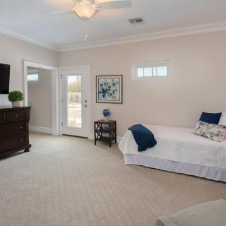 A spacious, modern bedroom featuring a single bed, dresser, and wall-mounted television.