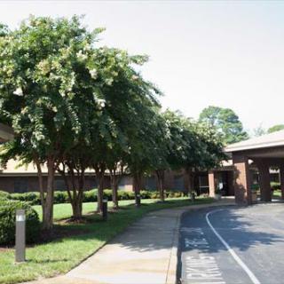 A serene view of a well-maintained building surrounded by lush trees and greenery.