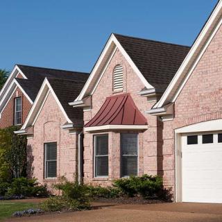 A row of suburban brick houses with gabled roofs and a garage.
