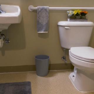 A clean and organized bathroom with a sink, toilet, towel, and decorative flowers.