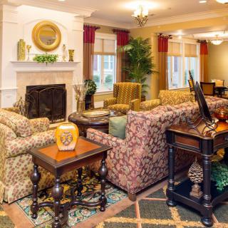 A cozy living room with patterned sofas, armchairs, a fireplace, and decorative elements.