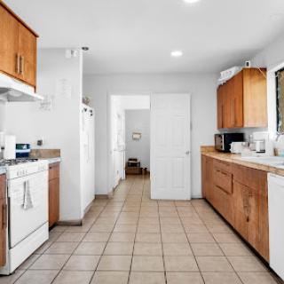 A modern kitchen featuring wooden cabinets and tiled flooring, illuminated by bright overhead lights.