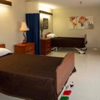 A hospital room with two beds and minimal furnishings.