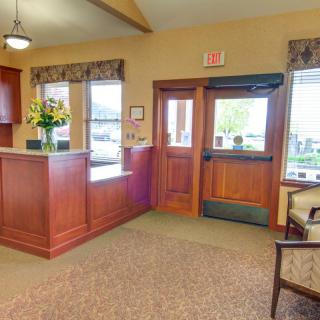 A reception area with a wooden desk, seating arrangements, and a main entrance.