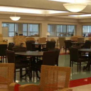 A spacious cafeteria with multiple tables and chairs arranged neatly.