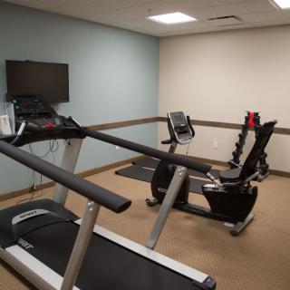 A modest gym with a treadmill and a stationary bike.